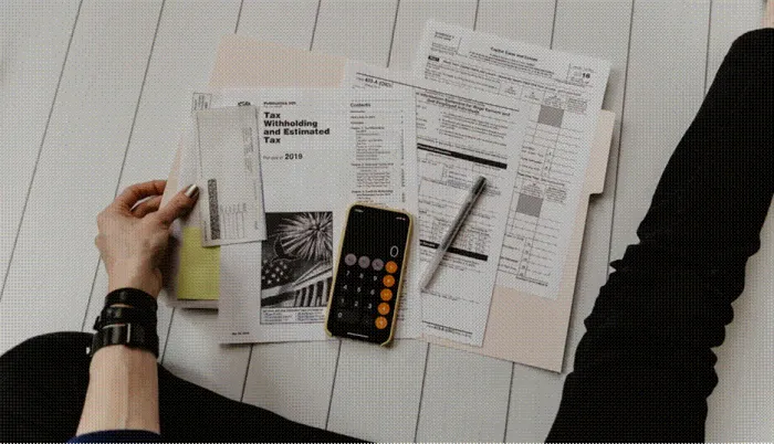 Title: Paper bills spread on a table while a phone calculator works out the totals - Description: Paper bills spread on a table while a phone calculator works out the totals