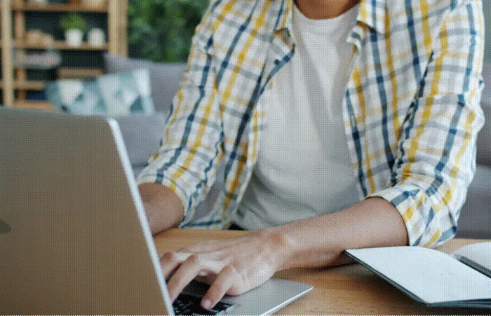 Title: Writer typing a content brief into an AI tool on a laptop at a home desk - Description: Writer typing a content brief into an AI tool on a laptop at a home desk