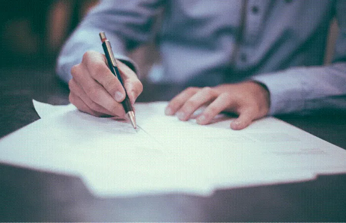 Title: Editor marking up a printed draft with a pen on a desk - Description: Editor marking up a printed draft with a pen on a desk